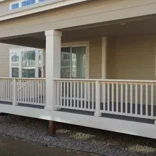 Beige house with porch, white railings, and supporting columns.