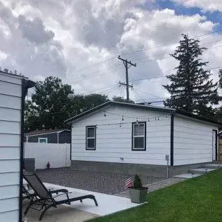 White house with black trim, string lights, and a small American flag in a yard.