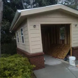 Tan garage with open door, brick base, and concrete driveway.