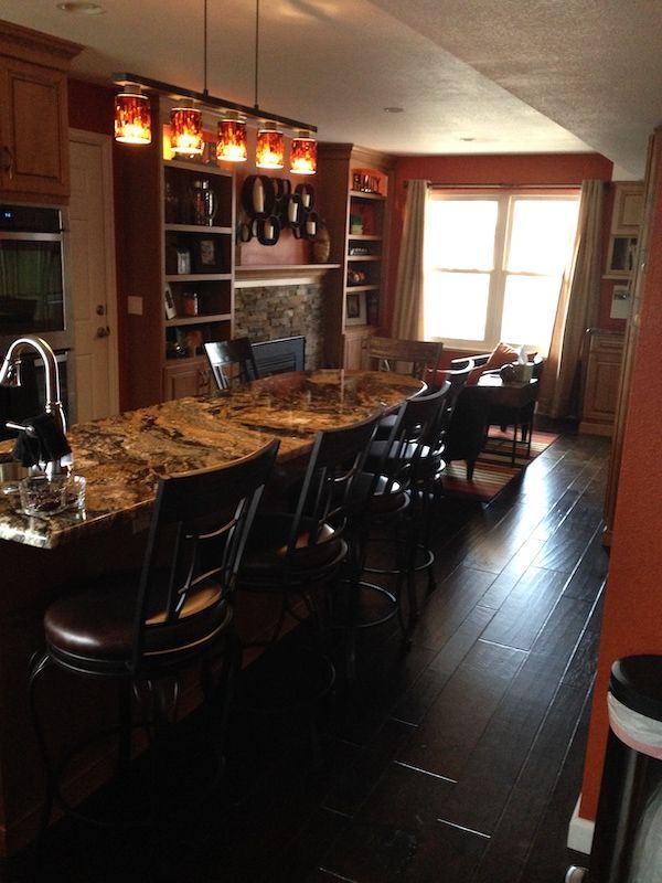 Kitchen with a long island, seating, dark wood floors, and warm-toned cabinets and walls.
