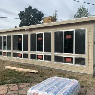 A long building with several large windows. Exterior walls are beige, and the windows have white frames.