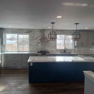 Modern kitchen with gray cabinets, a blue island, and stainless steel appliances.