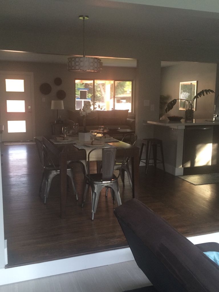 Dining room with table and metal chairs. Dark wood floor, doorway, and pendant light.