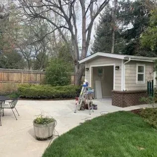 Backyard with a detached garage, patio, grass, and a wooden fence.
