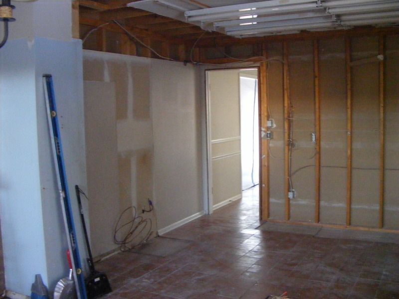 Interior view of a room under construction with exposed studs, unfinished walls, and doorway. Concrete floor.