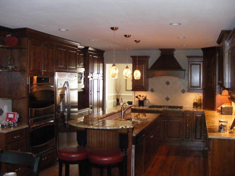 Dark wood kitchen with granite countertops, stainless steel appliances, and pendant lights.