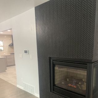 Black tiled fireplace with modern black frame, adjacent to a white wall.