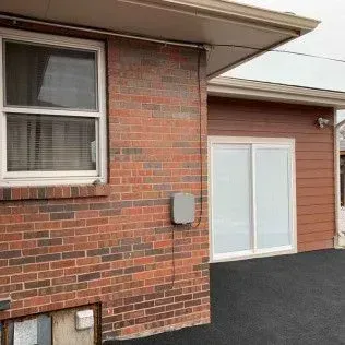 Brick building exterior with a window, sliding glass door, and asphalt.