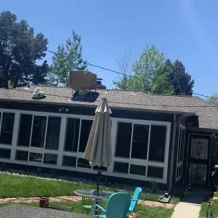 House with patio, umbrella, and a blue chair under a clear blue sky.