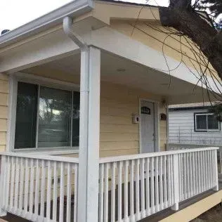 Yellow house with white porch and railing.