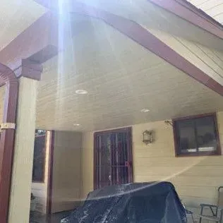 Covered patio with cream walls, burgundy trim, and a covered grill.