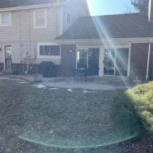 Backyard with a concrete patio, sliding glass doors, and a two-story house with siding.