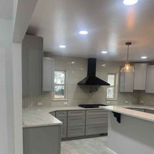 Gray kitchen with cabinets, countertops, and a black range hood.
