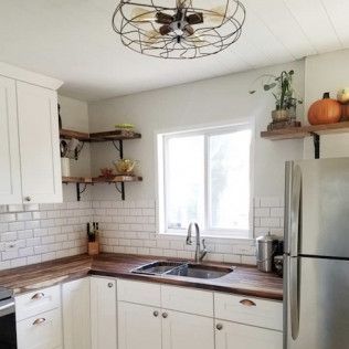 White kitchen with butcher block countertops, white cabinets, subway tile, and floating shelves.