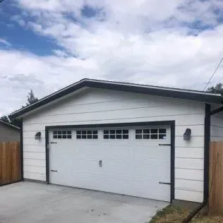 White garage with black trim, a closed garage door, and a concrete driveway.