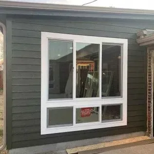 White-framed window on a green-sided building. The window has three upper panes and three lower panes.