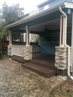 Covered outdoor patio with stone columns, composite decking and railing.