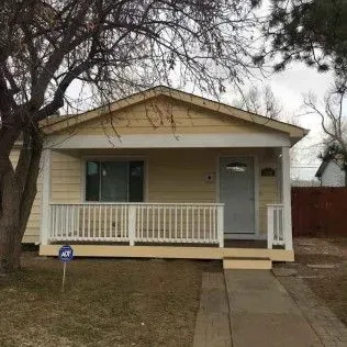 Yellow house with white porch and front door, a tree to the left, and a sidewalk leading to the entrance.