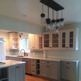 Modern kitchen with light cabinets, stainless steel appliances, and a hanging light fixture.