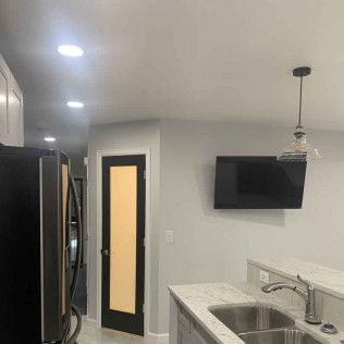 Kitchen with black appliances, a black-framed door with a yellow panel, and a mounted TV.