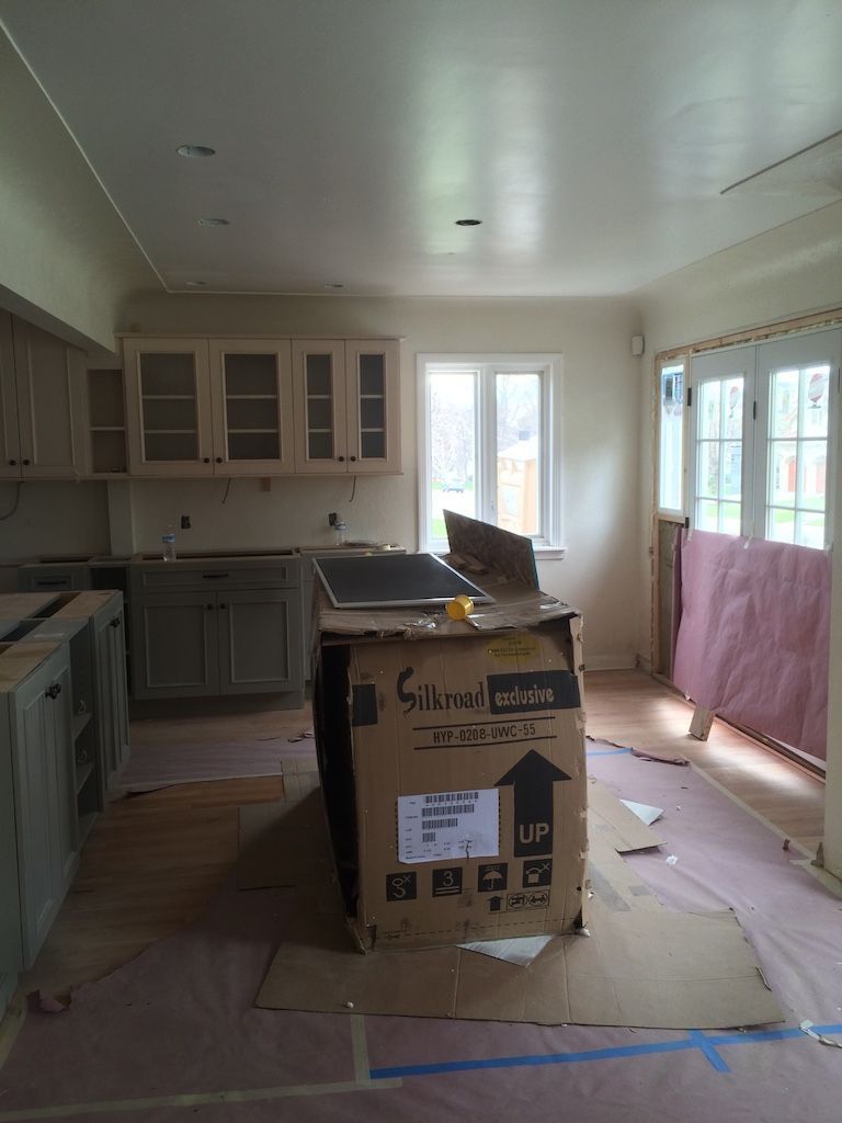 Kitchen under construction with cabinets, island, and flooring partially installed.