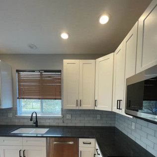 White kitchen cabinets with black countertops and stainless steel appliances.