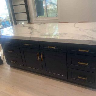 Dark blue kitchen island with marble countertop and gold hardware.
