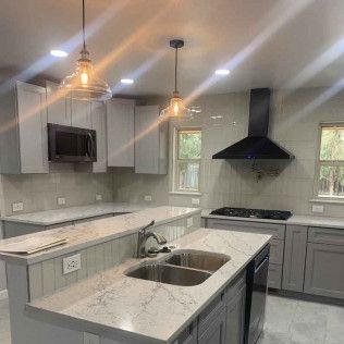 Modern kitchen with gray cabinets, white countertops, and stainless steel appliances.