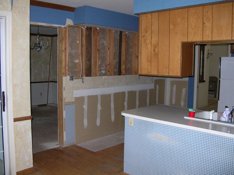 Kitchen remodel with exposed studs, unfinished walls, and existing cabinets.