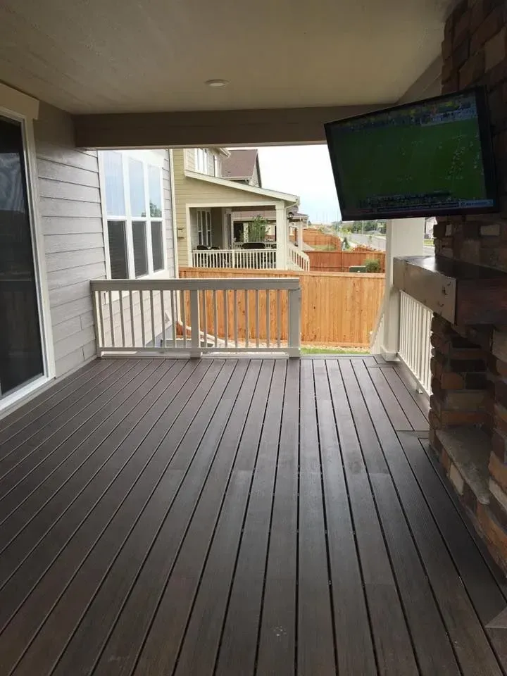 Covered patio with a mounted TV, composite decking, and a view of neighboring houses.