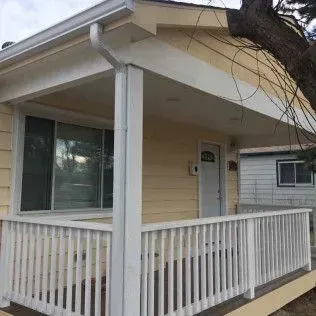 Yellow house with a white porch, railing, and trim.