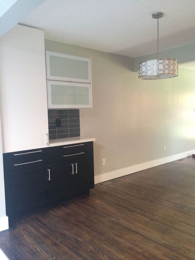 Black and white kitchen cabinets with glass-front uppers, white countertop, and dark wood flooring.