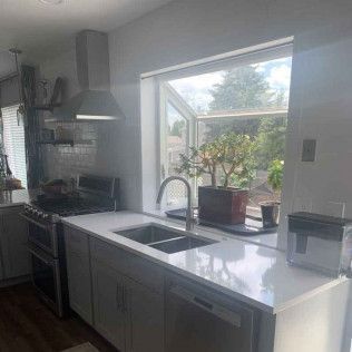 Kitchen with stainless steel appliances, white cabinets, and a window with a view of a tree.