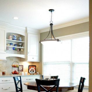 Kitchen with white cabinets, round table, chairs, pendant light, and windows with blinds.