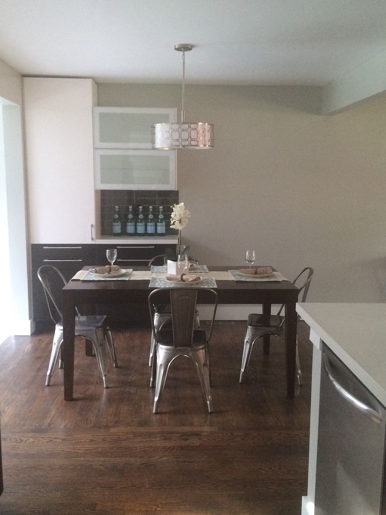 Dining room with wooden table, metal chairs, and pendant light fixture.