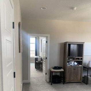 Hallway with open doorways, wooden cabinet, and neutral walls.