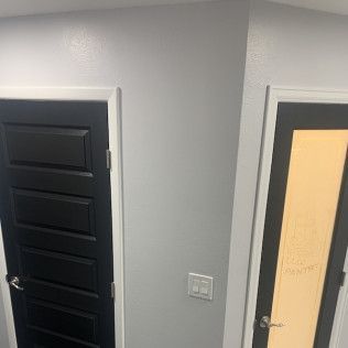 Two doors, one black, one with yellow frosted glass, against gray walls. White door frames.