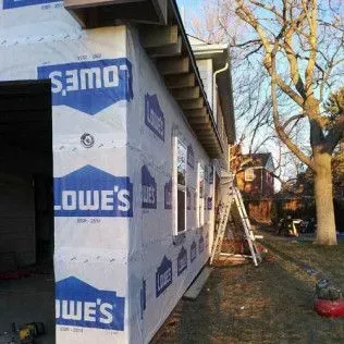 Exterior of a building under construction, wrapped in blue and white Lowe's house wrap.