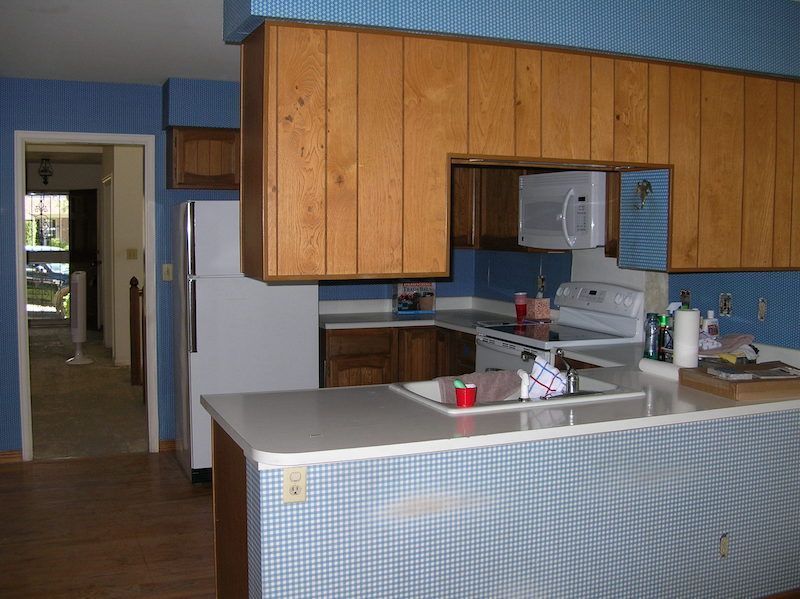 Kitchen with wood cabinets, blue walls, and a white countertop.