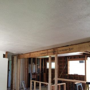 Interior renovation: exposed wooden beams, studs, and partially demolished walls, unfinished ceiling.
