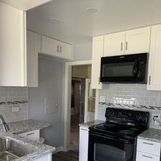 White kitchen with stainless steel appliances and backsplash.