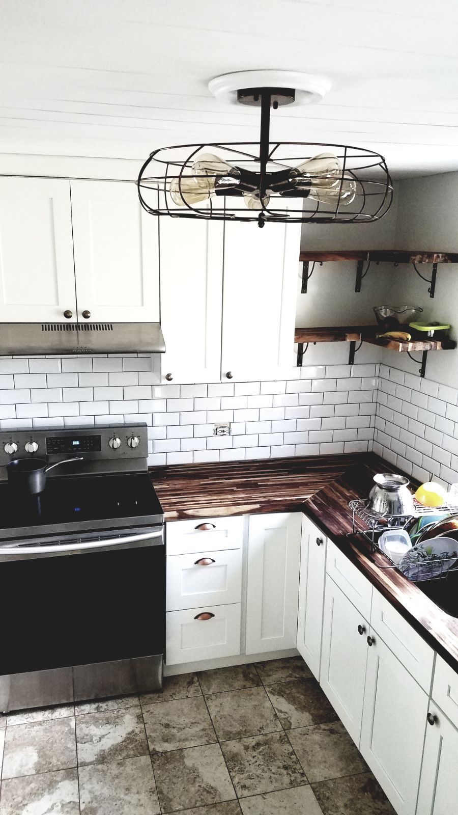 Kitchen with white cabinets, black stove, wood countertops, and a decorative ceiling fan.