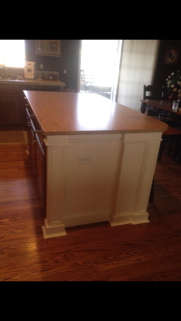 Kitchen island with a light-colored countertop and white base, set on a wood floor.