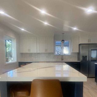 Modern kitchen with large white island, cabinets, and a refrigerator.