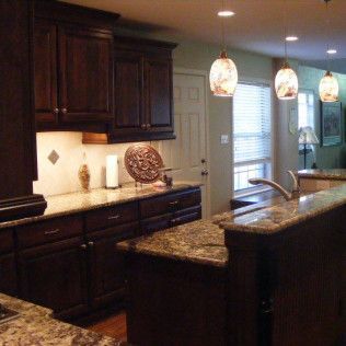 Kitchen with dark cabinets, granite countertops, and pendant lights.