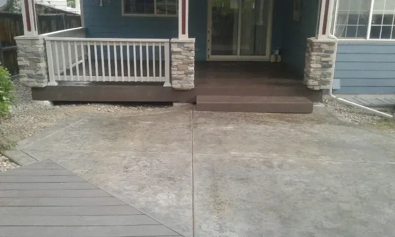 A back patio with a porch, concrete, and composite decking. The house is blue.