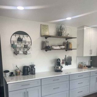 Kitchen with gray and white cabinets, open shelves, and coffee-making station.