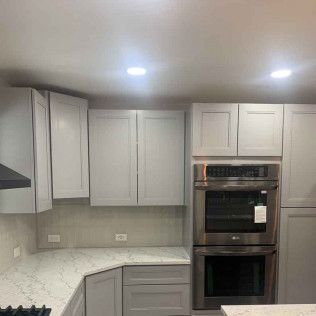 Kitchen with gray cabinets, a double oven, and a white countertop.