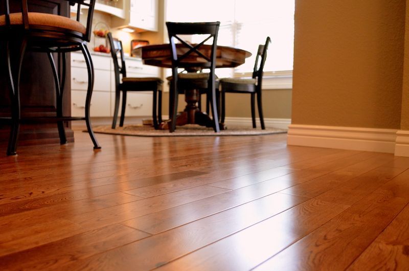 Shiny hardwood floor in a kitchen with a round table and chairs.