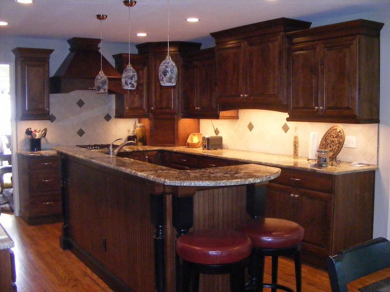 Kitchen with dark wood cabinets, a granite countertop, and pendant lights.